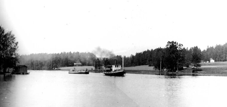 Kuriren med pråm lastad med malm från Stortägtsgruvan i Semla till Västanfors hytta, fotograferad i Fagersta omkring år 1900 med torpet Lilla Fagersta till höger
